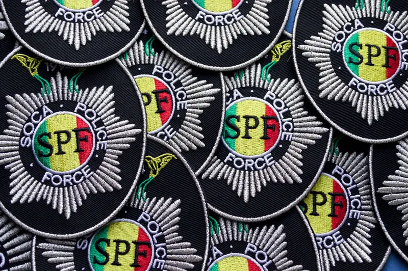 A batch of multi-colour embroidered service badges laid out together.