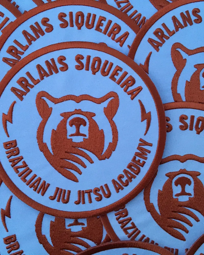 Round embroidered jiu jitsu academy patches in orange and blue.