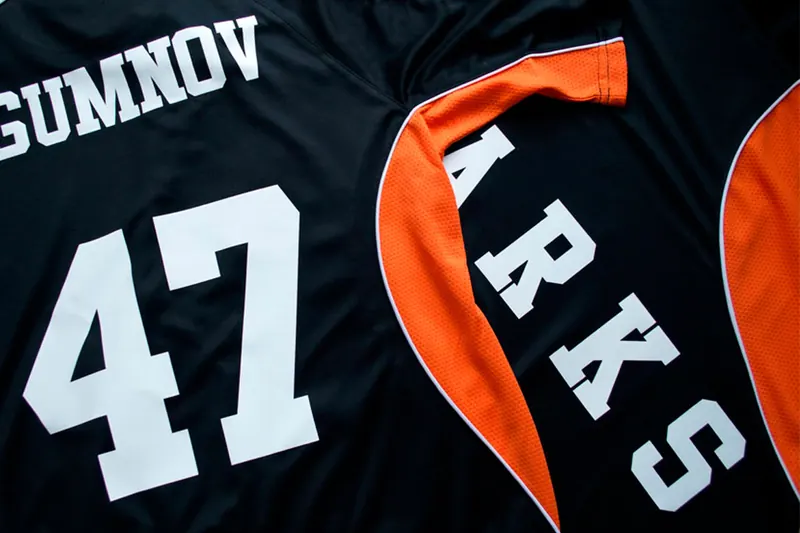 Printed names and numbers on a set of black and orange sports jerseys.