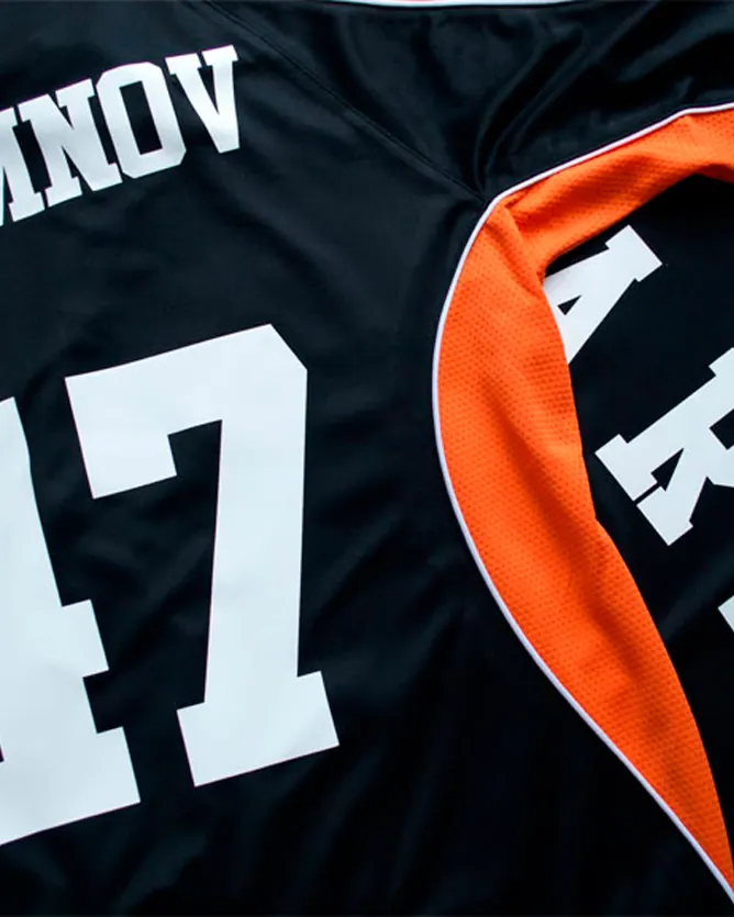 Player name and number heat-pressed in white vinyl onto a black and orange sports jersey.