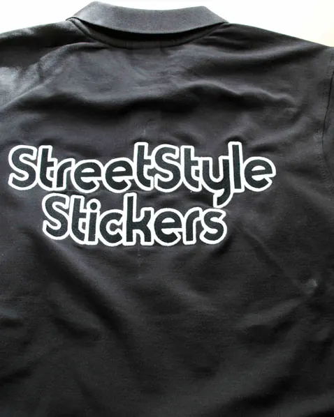 Company name printed in white lettering across the back of a black polo shirt.