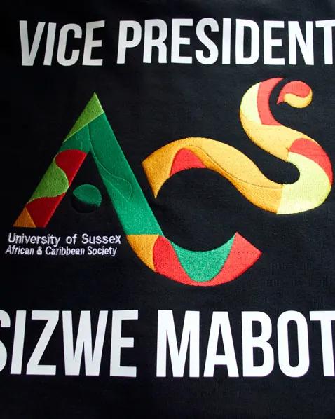 Multi-colour society logo and name printed on a black t-shirt.