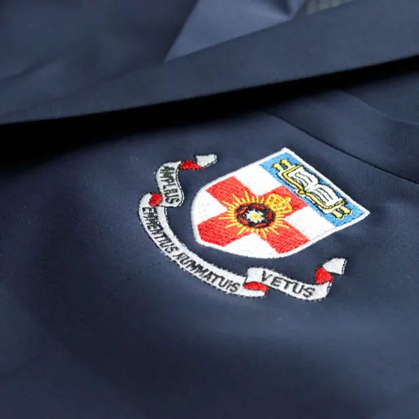 Detailed multi-colour crest embroidered on the breast pocket of a navy blazer.