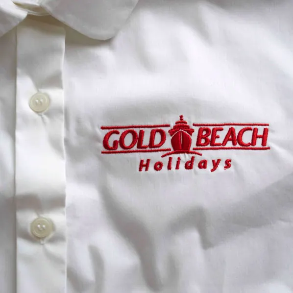 White cotton shirt with a red and black travel company logo embroidered on the chest.