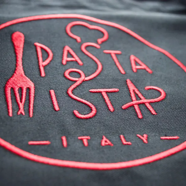 Hand-drawn restaurant logo embroidered in red thread on a charcoal apron.
