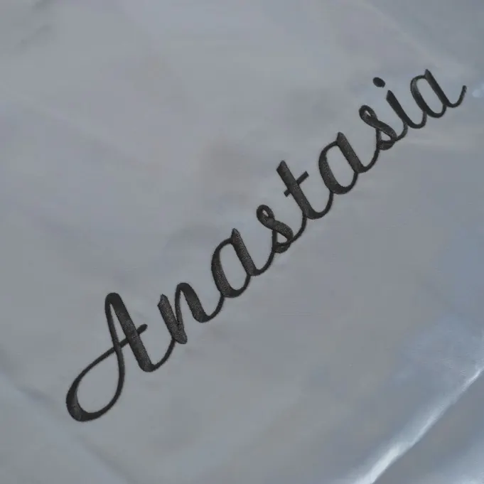 The name Anastasia embroidered in fine grey script on a white robe.